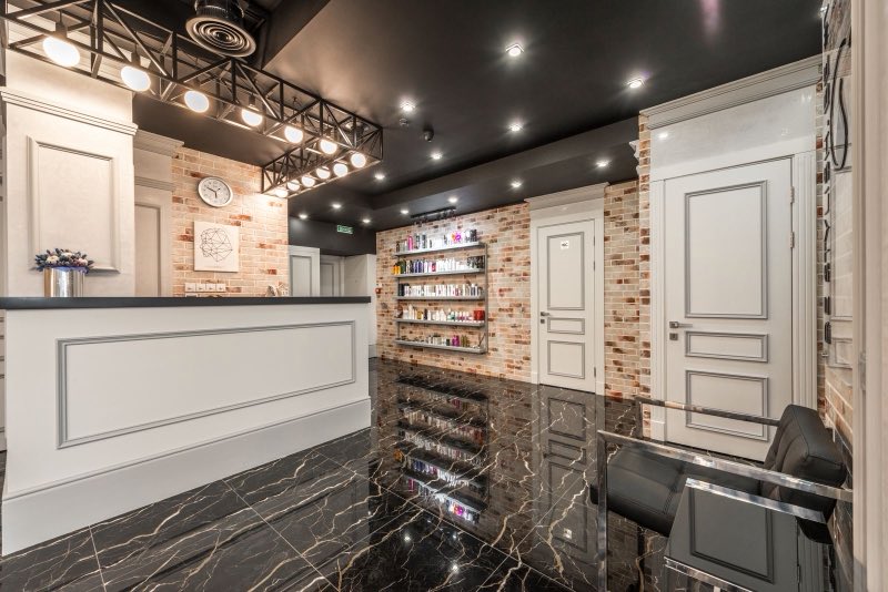 The reception counter of a small clinic, with a shelf of unbranded bottles behind it and doors through to the treatment rooms.